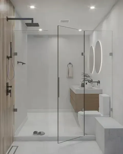 Modern bathroom with glass shower, floating vanity, oval mirror, and white tiled walls
