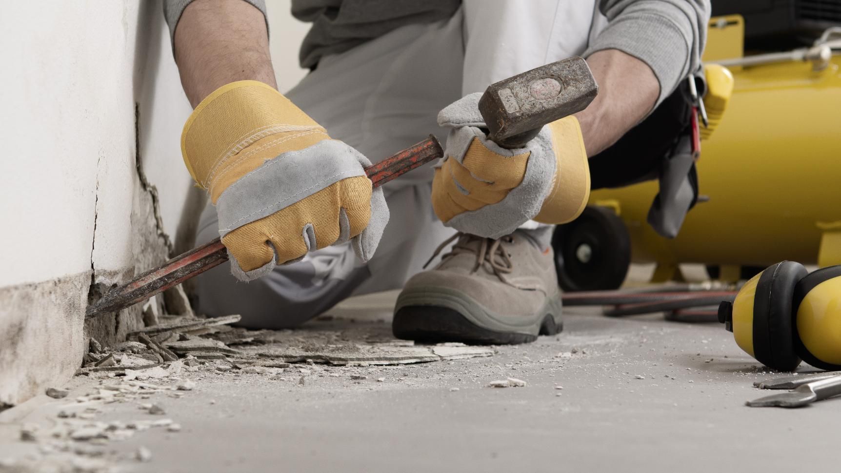 A man is breaking a wall with a hammer.