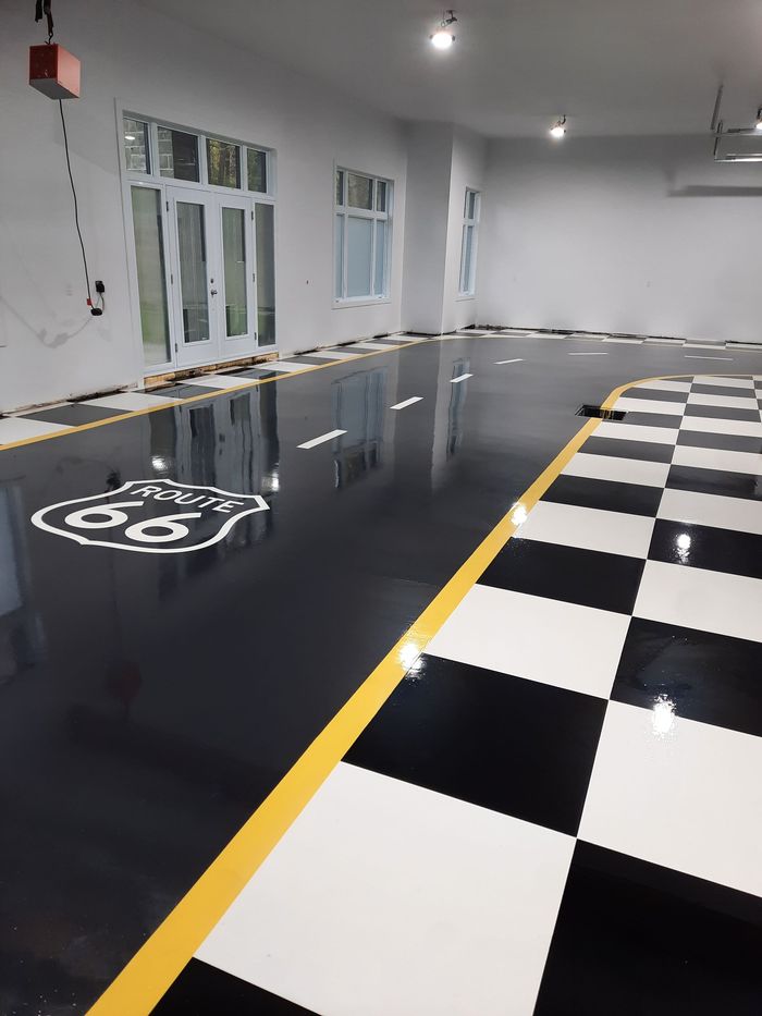 Sol intérieur peint représentant une route avec un panneau de la Route 66 et un motif à carreaux. Couleurs : noir, blanc et jaune.