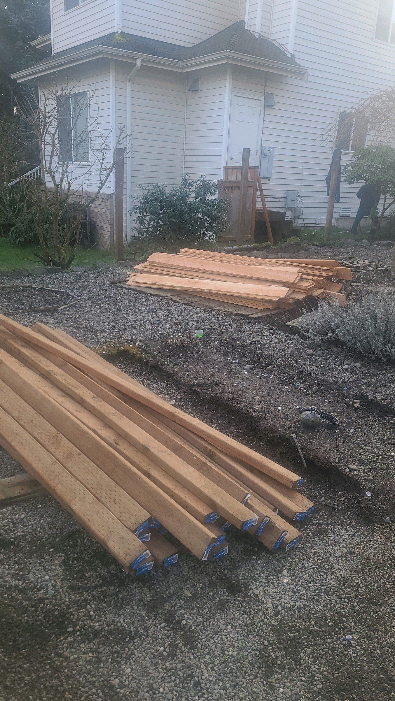 Construction site. Wood beams in foreground, building in background, gravel and dirt.