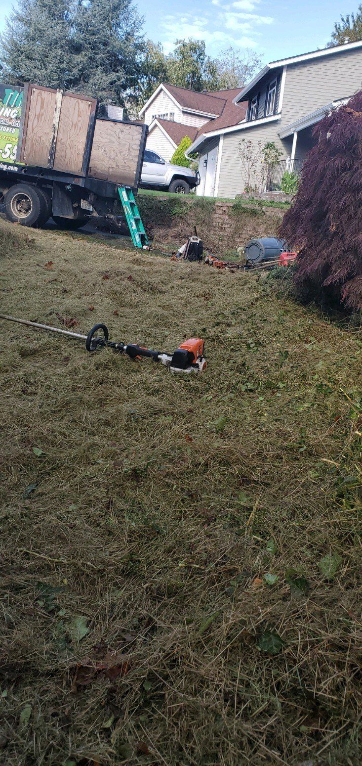 A lawn being mowed on a steep hill with equipment and a truck present.