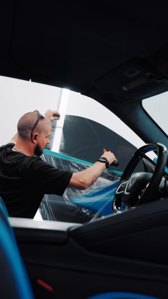 Person sitting in a car, fastening a seat belt while looking out the window