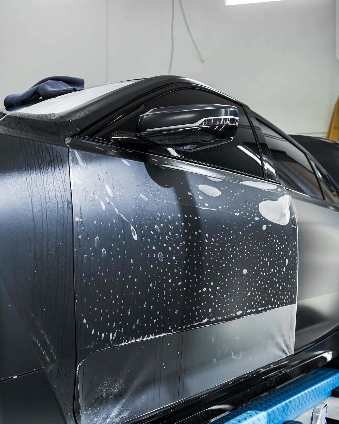 Black sports car side view with water spots in a garage or workshop