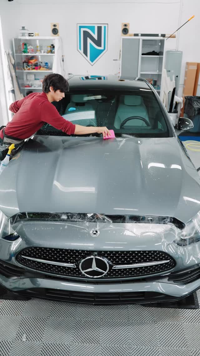 Person wiping a silver Mercedes in a car detailing garage