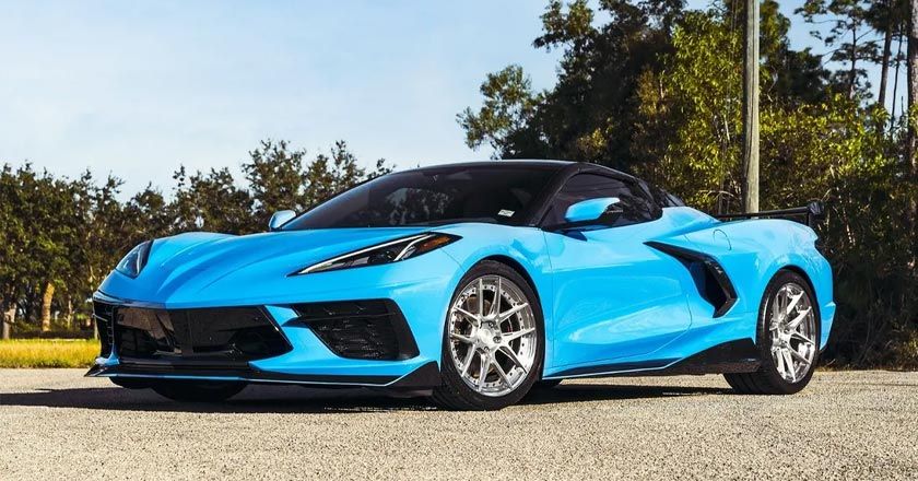 A blue corvette is parked on the side of the road.