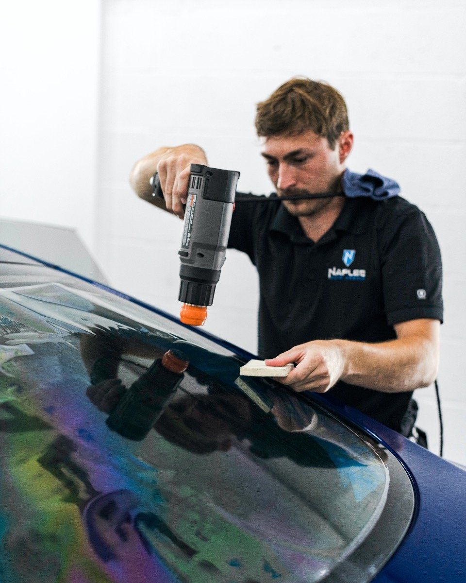 A man is working on a car windshield with a drill.