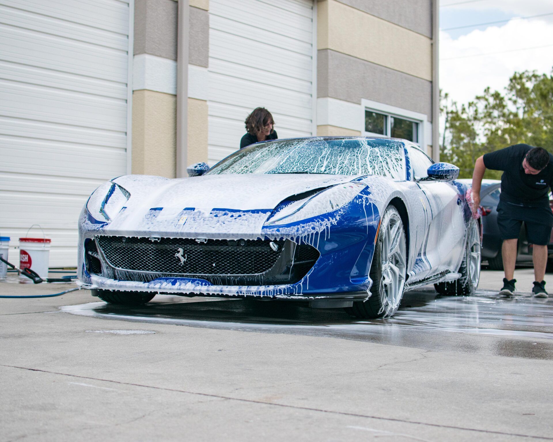 A man is washing a blue and white sports car