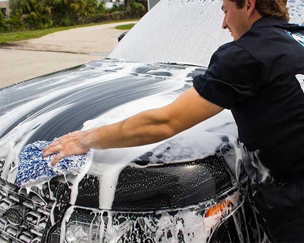 A man is washing a car with soap and water