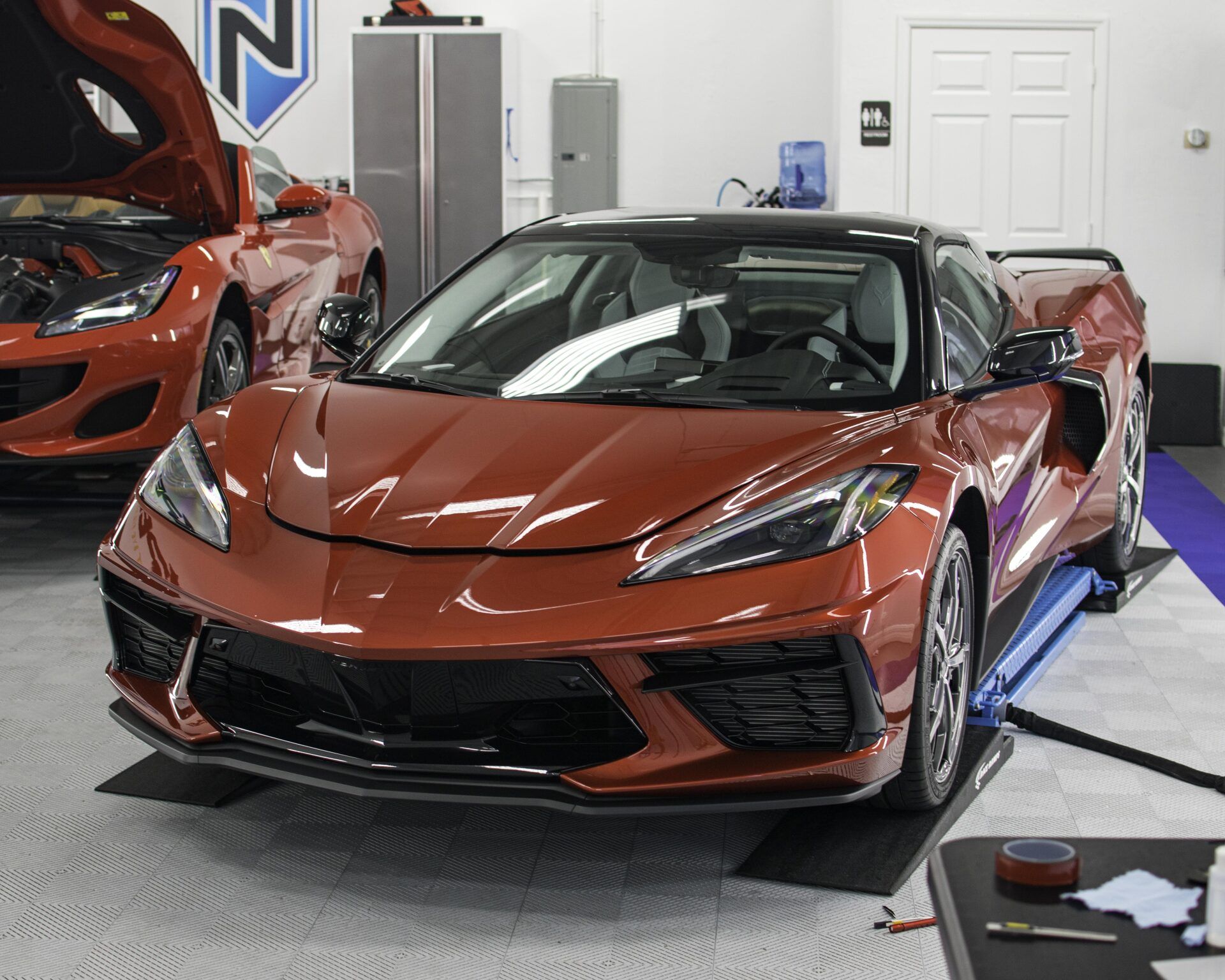 A red sports car is parked in a garage with the hood up.