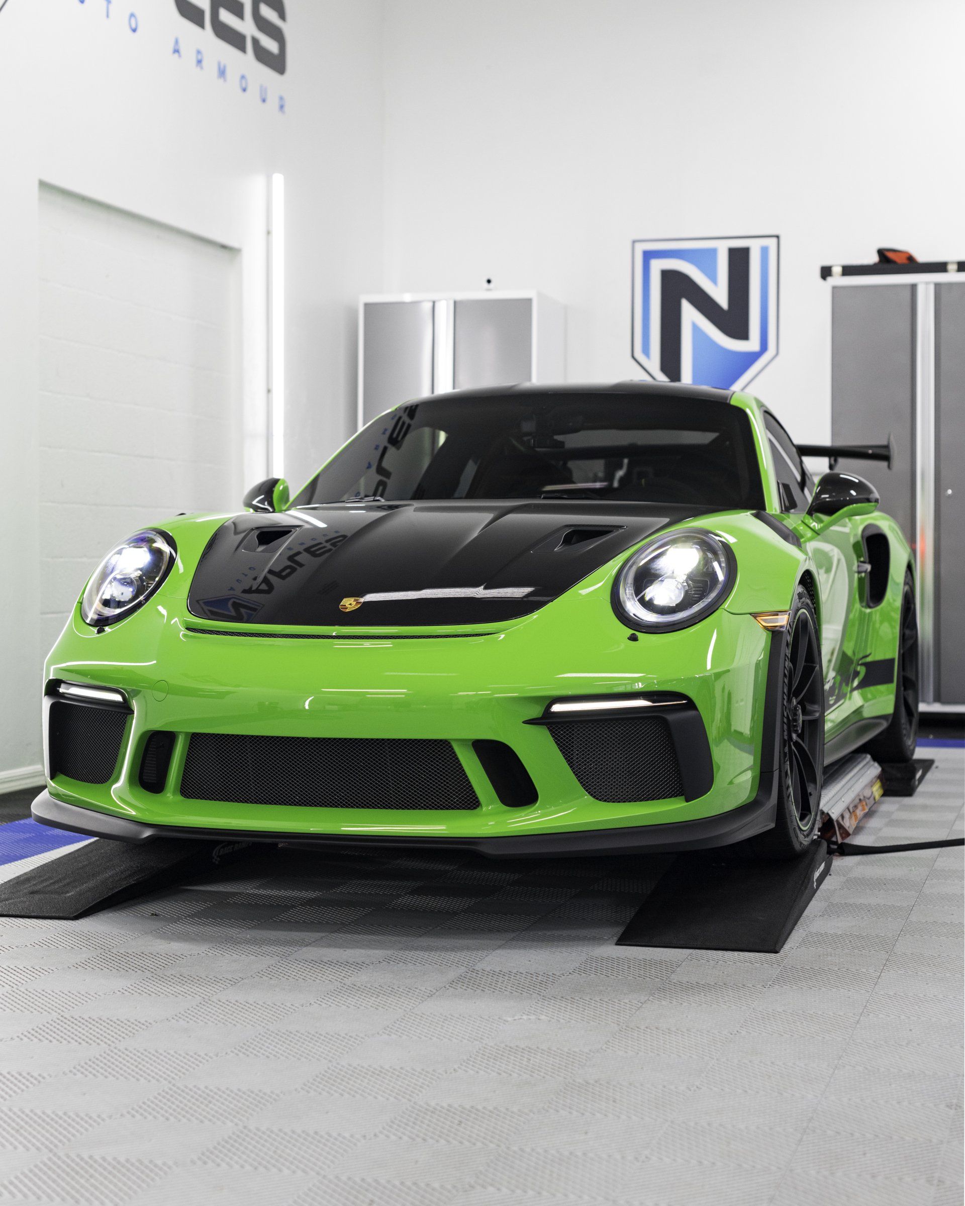 A green porsche 911 gt3 rs is parked in a garage.