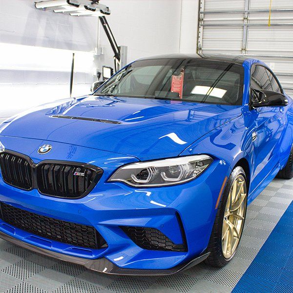 A blue bmw m2 is parked in a garage.