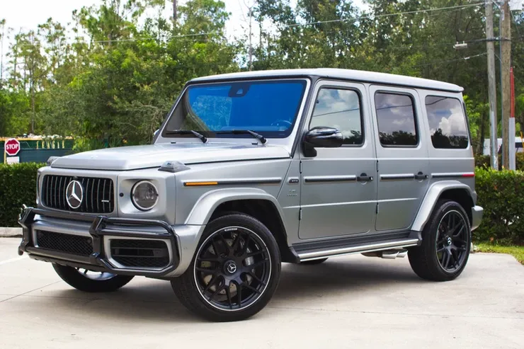 A silver mercedes benz g63 amg is parked in a parking lot.
