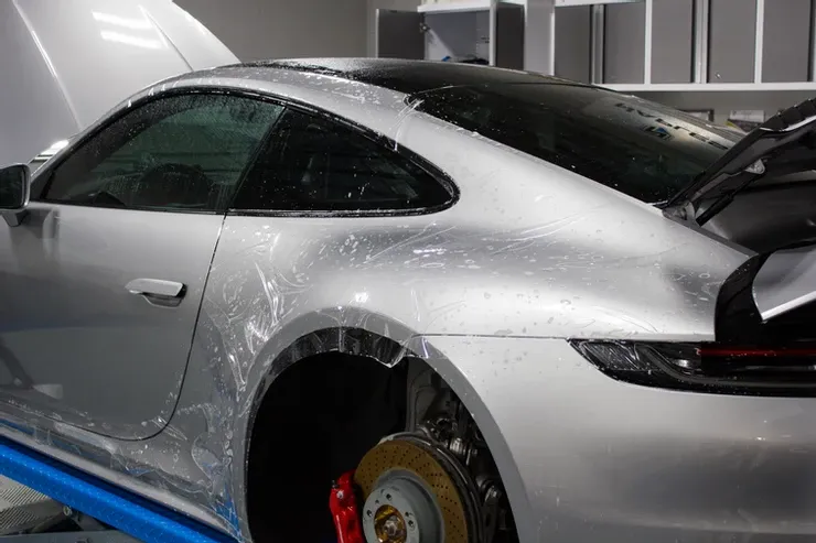 A silver sports car is sitting on top of a blue lift in a garage.