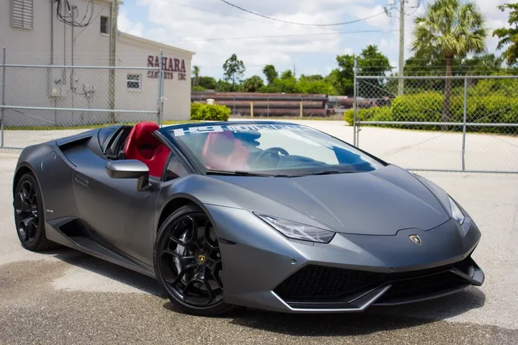 A gray lamborghini huracan is parked in a parking lot in front of a building.