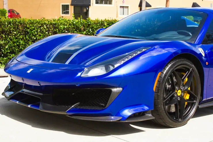 A blue ferrari 488 pista is parked on the side of the road.