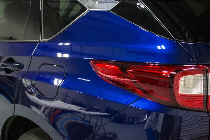 A blue car with a red tail light is parked in a garage.