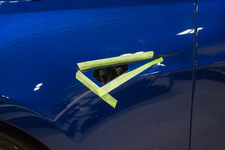 A close up of a blue car with green tape on it.
