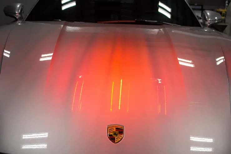 The hood of a white porsche is glowing red.