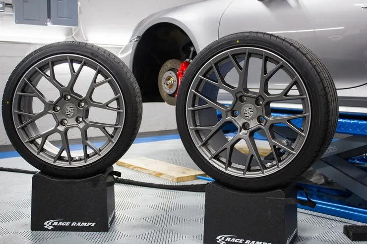 Two wheels are sitting on top of each other in front of a silver car.