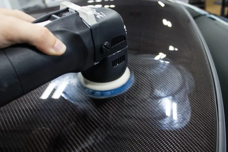 A person is polishing a car with a machine.
