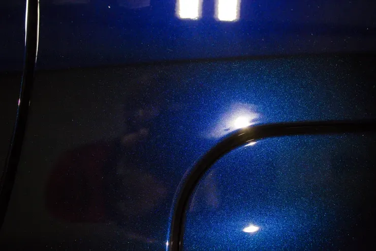 A close up of a blue car with a light shining on it.