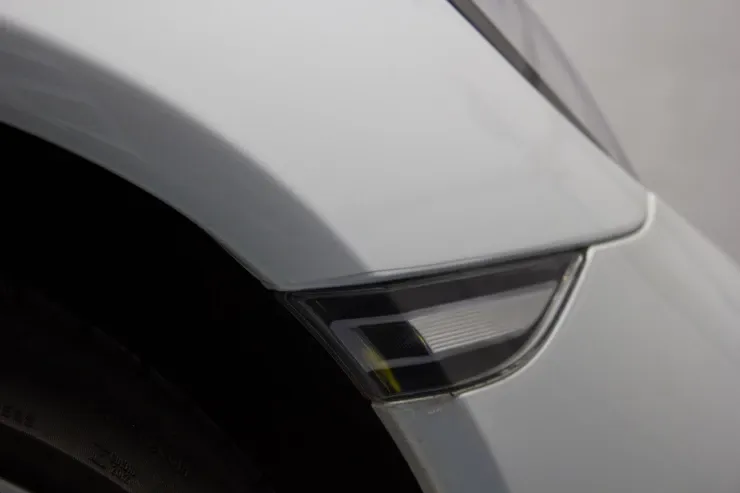 A close up of a white car fender with a light on it.