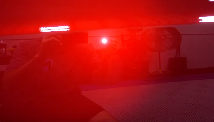 A person is taking a picture of a red light in a dark room.