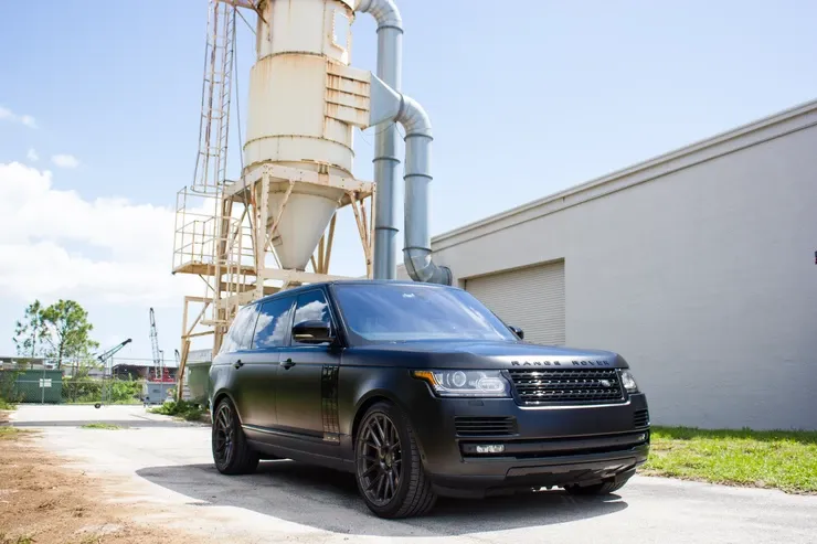 A black range rover is parked in front of a building.