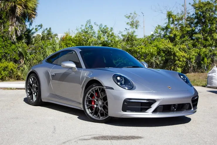 A silver porsche 911 is parked in a parking lot.