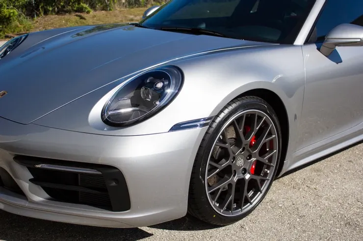 A silver porsche 911 is parked on the side of the road.
