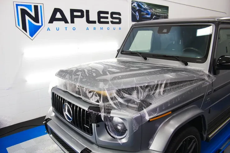 A silver mercedes benz g63 is wrapped in plastic.