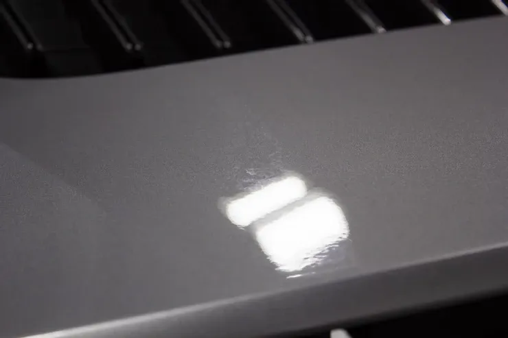 A close up of a car hood with a reflection of a light on it.