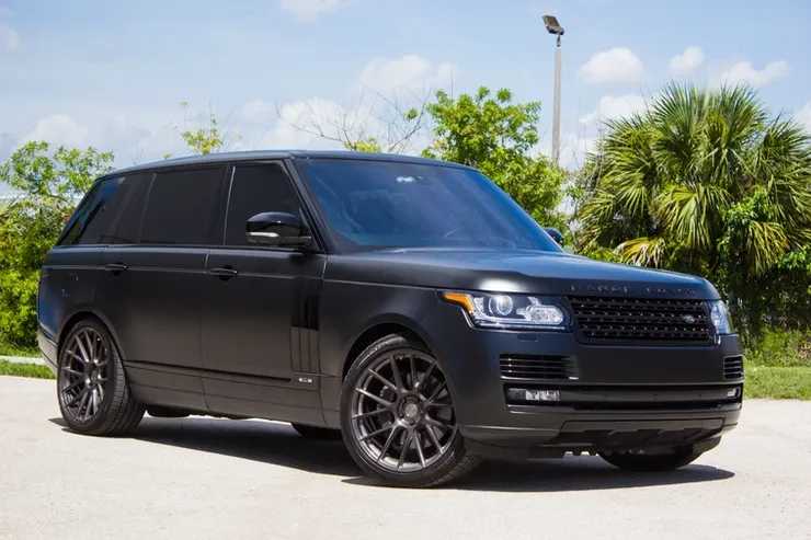 A black range rover is parked on the side of the road.