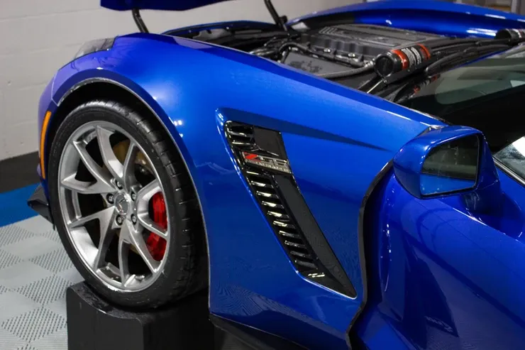 A blue sports car with the hood open is on display