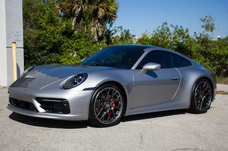 A silver porsche 911 is parked in a parking lot.