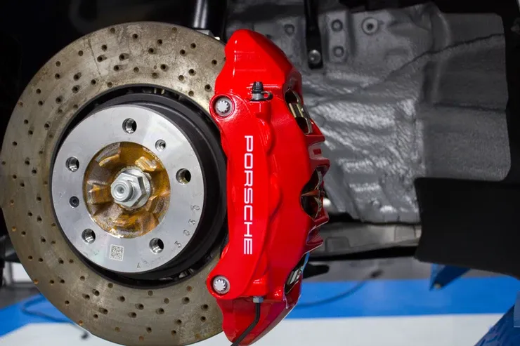 A close up of a red porsche brake caliper on a car.