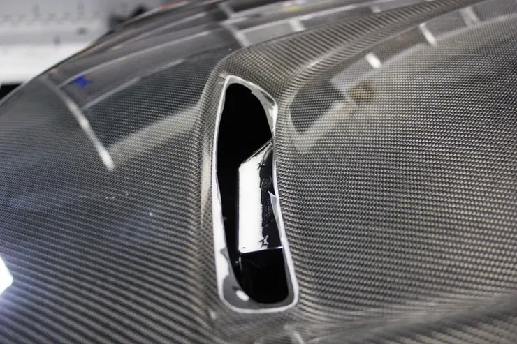 A close up of a car hood with a hole in it