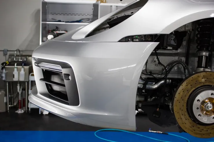 A silver sports car is being worked on in a garage.