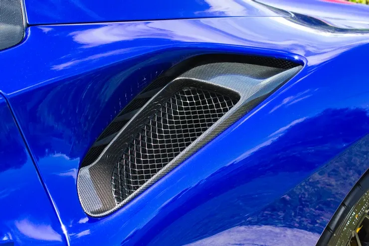 A close up of a blue sports car with a grille on the side.