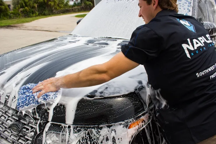 A man in a navy shirt is washing a car