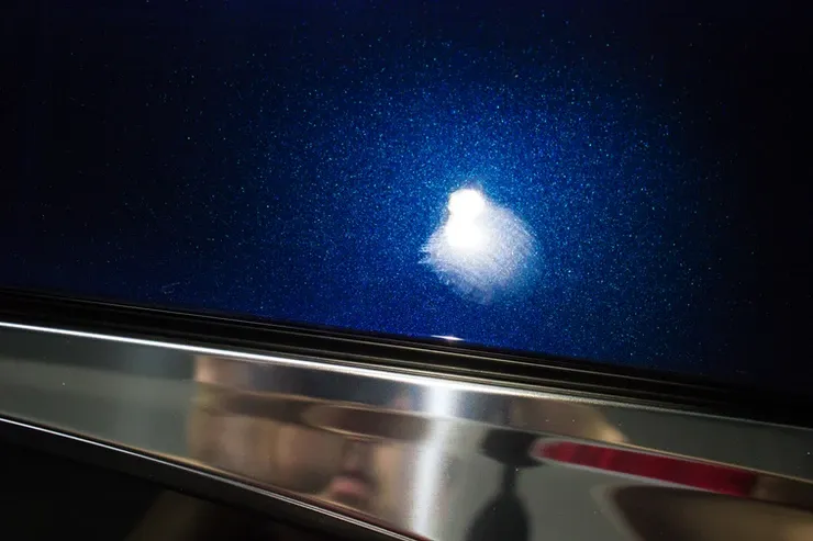 A close up of a blue car with a white spot on it.