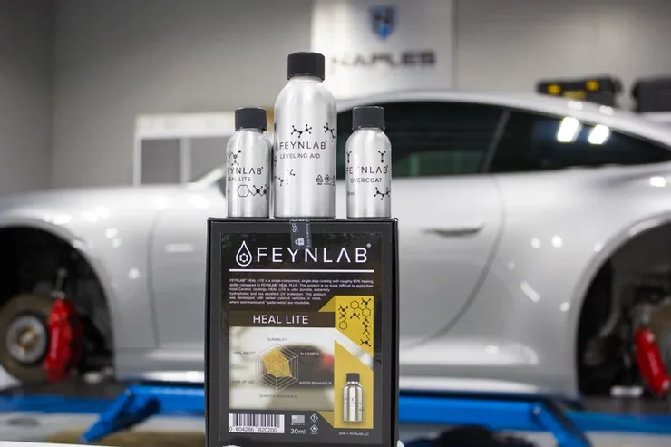 A box of bottles is sitting in front of a car on a lift.