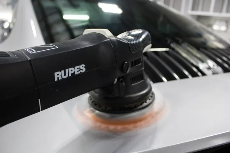 A close up of a machine polishing a car 's hood.