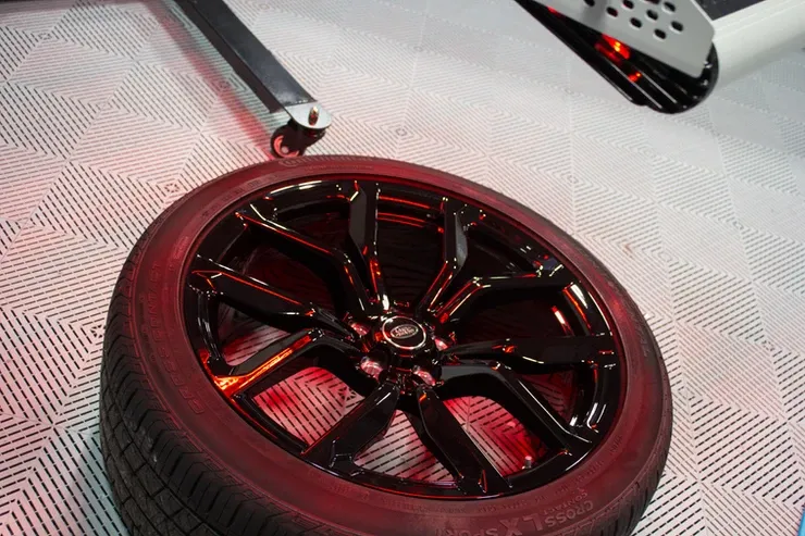 A black tire is sitting on a white tile floor.