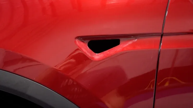 A close up of the side of a red tesla model s.