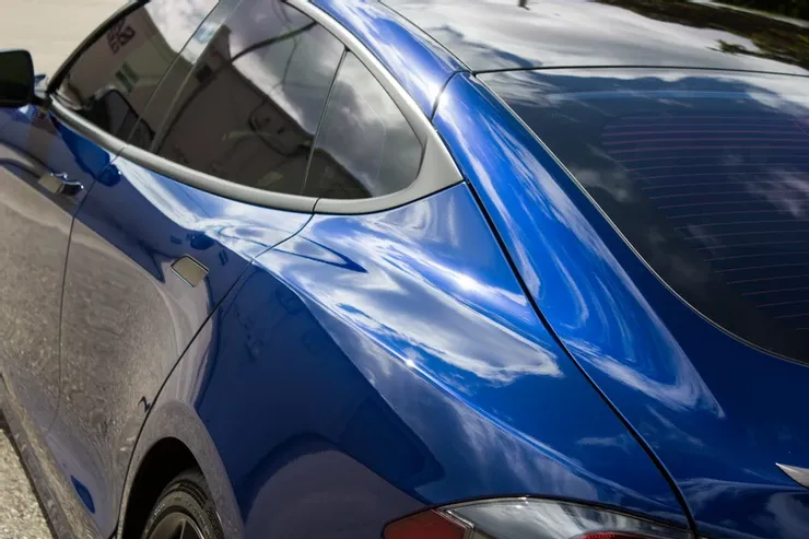 A blue car is parked on the side of the road