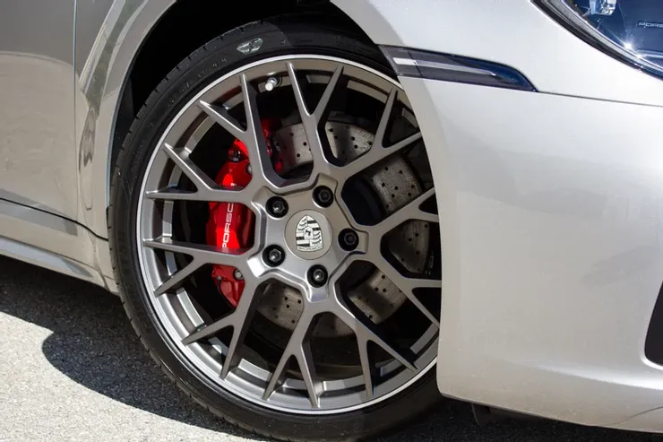 A close up of a silver porsche with red brake calipers