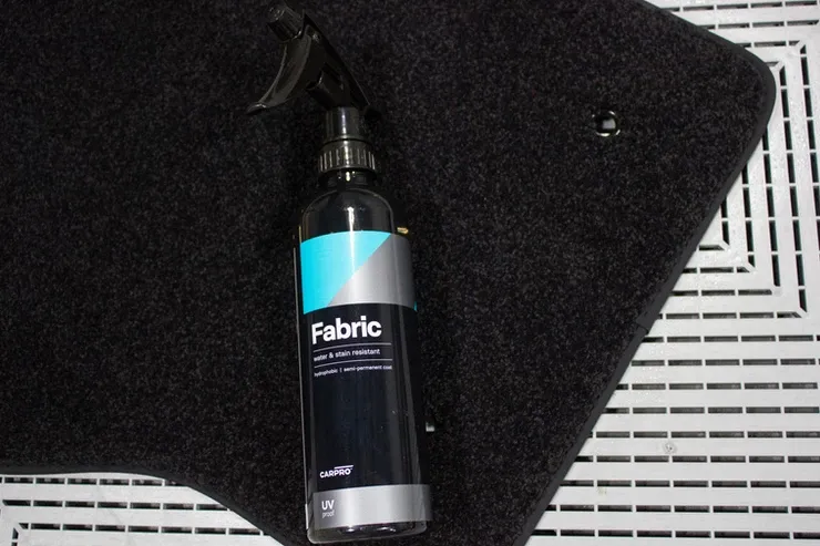 A bottle of fabric cleaner is sitting on top of a black mat.