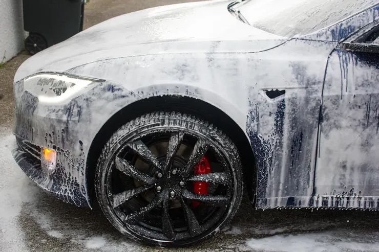 A tesla model s is covered in foam while being washed