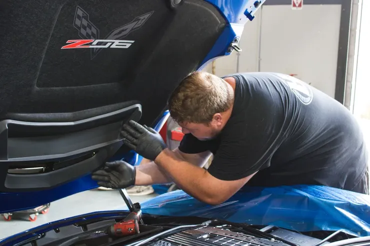 A man is working under the hood of a corvette